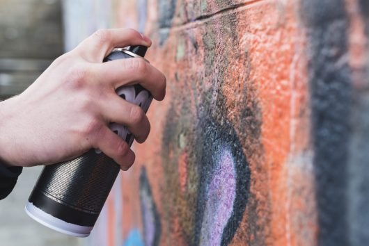 man-s-hand-drawing-graffiti-wall-with-aerosol-can